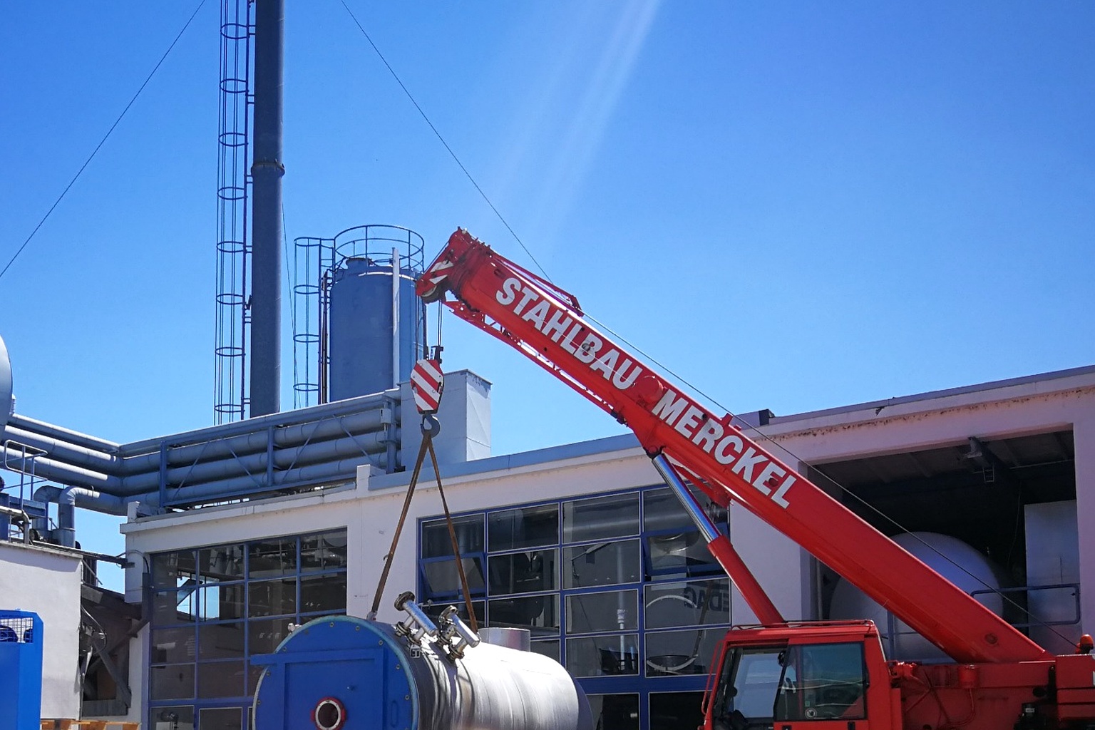Roter Stahlbau-Merckel-Kran beim Heben eines Industriebauteils